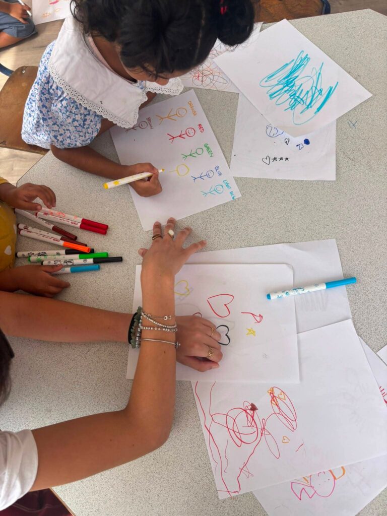 Mani di bambine che disegnano cuori e scritte su fogli bianchi