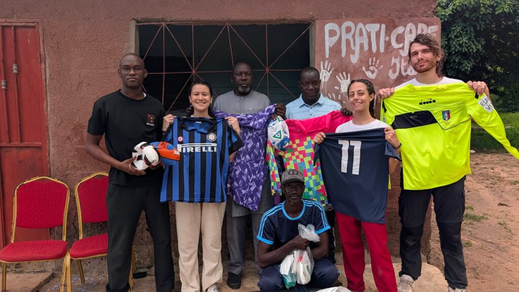 Volontari e ragazzi mostrano le magliette sportive donate
