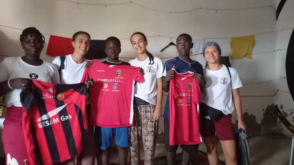 Volontari e ragazzi mostrano le magliette sportive donate