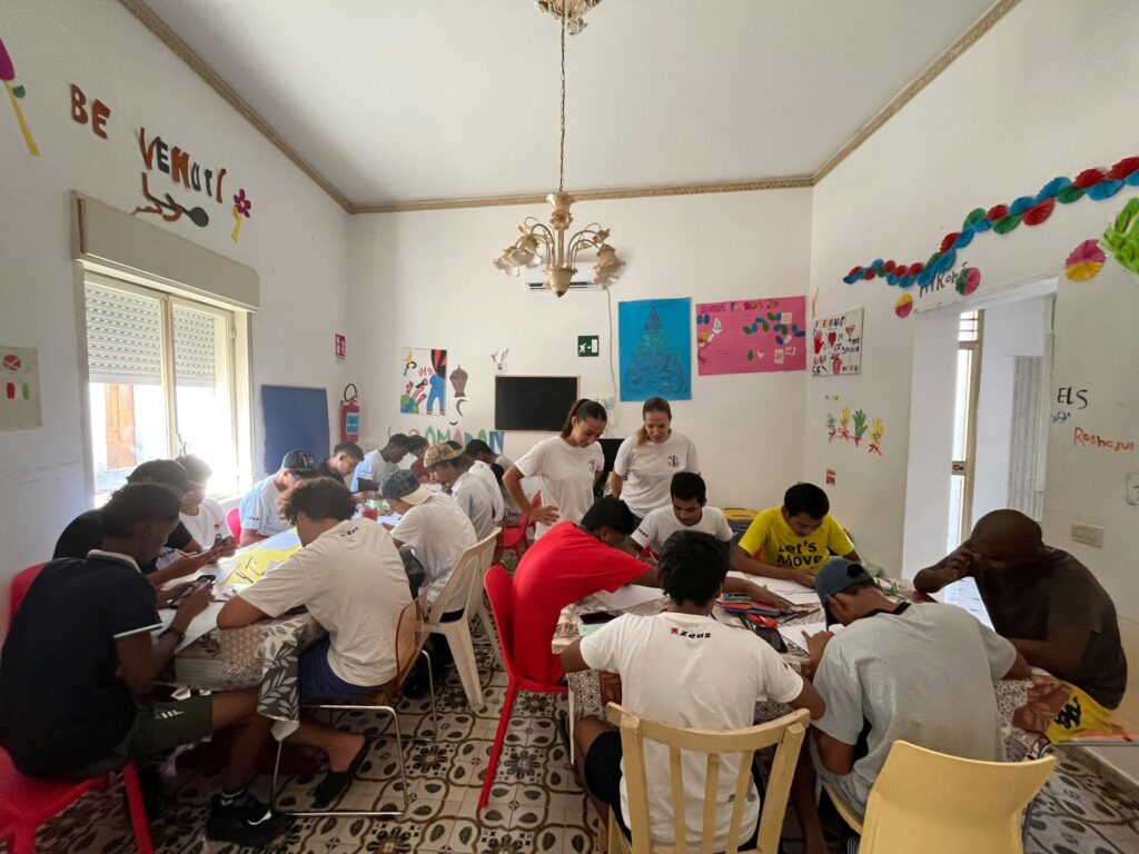 Ragazzi e volontarie seduti ai tavoli in una grande sala decorata