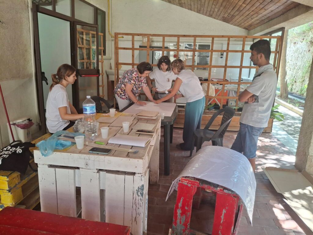 Ragazzi e volontarie al lavoro ai tavoli sotto una veranda