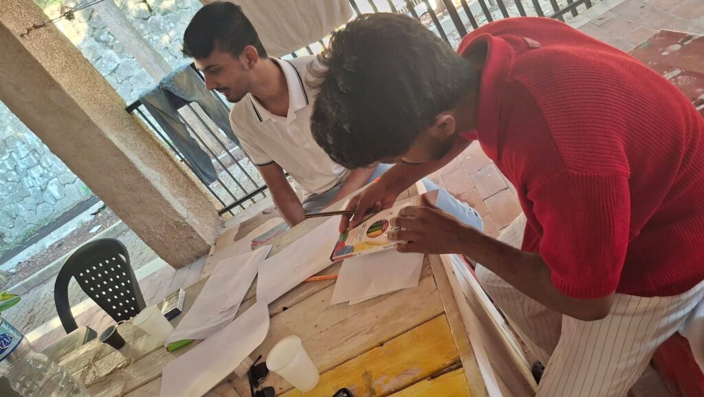 Ragazzi e volontarie al lavoro ai tavoli sotto una veranda