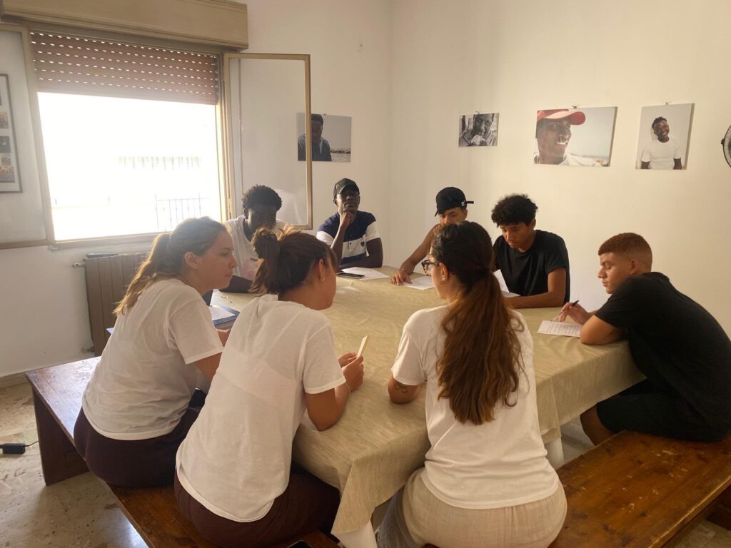 Volontarie e ragazzi al lavoro attorno a un tavolo durante un laboratorio