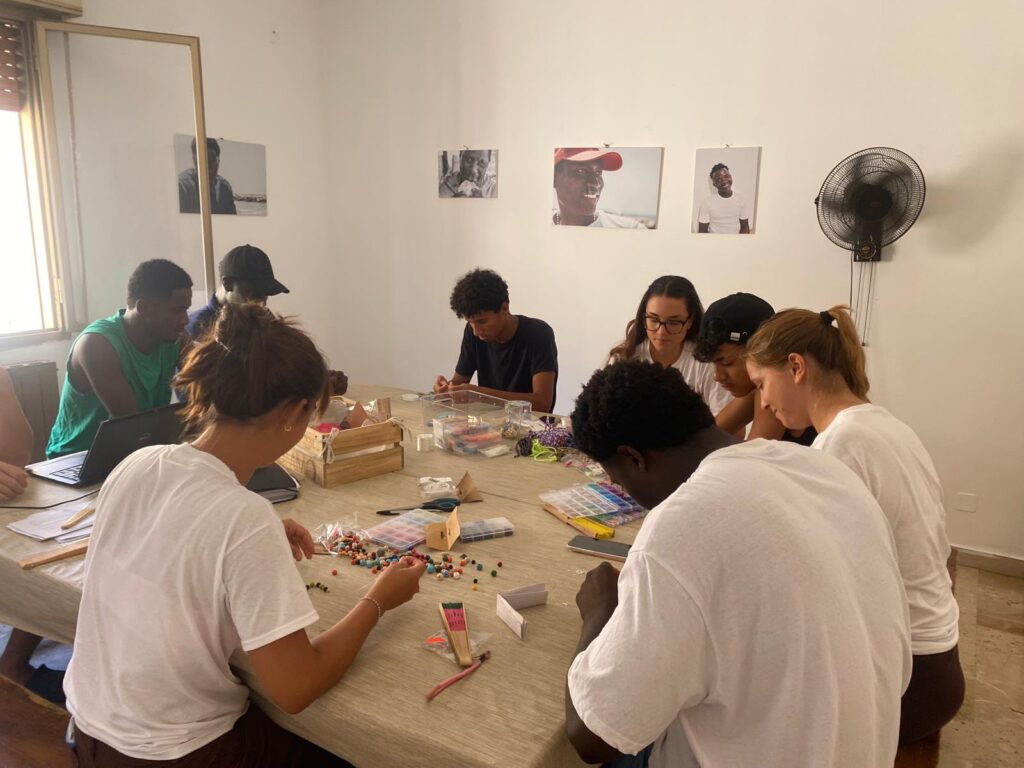 Volontarie e ragazzi al lavoro attorno a un tavolo durante un laboratorio