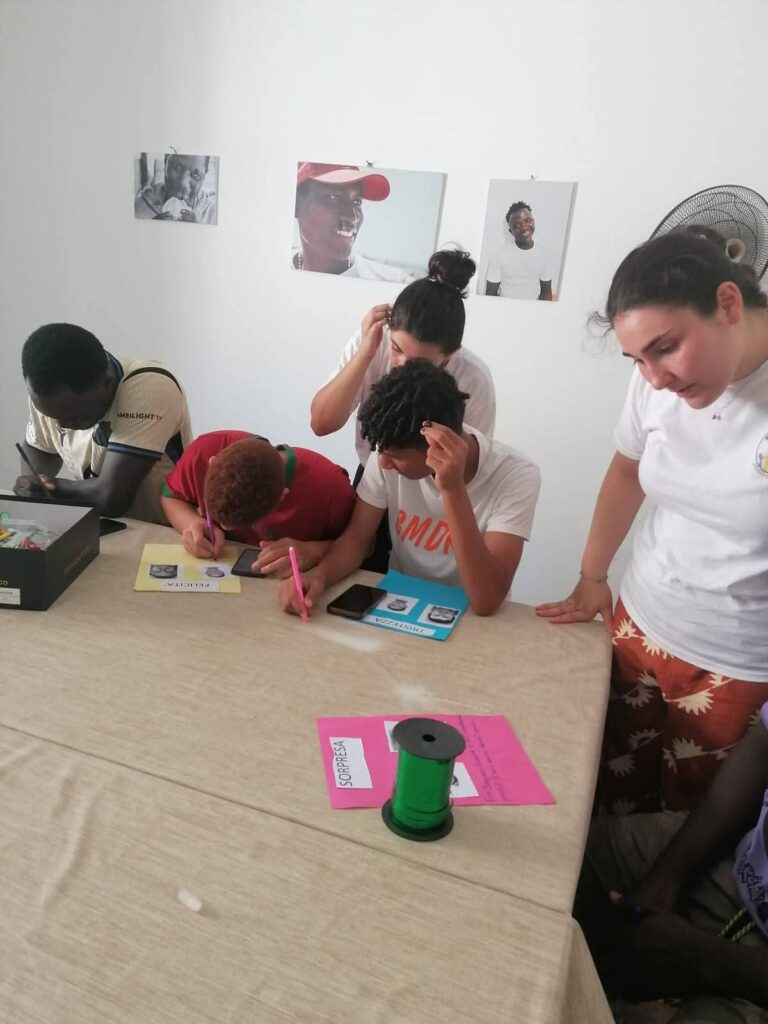 Volontarie e ragazzi al lavoro attorno a un tavolo durante un laboratorio