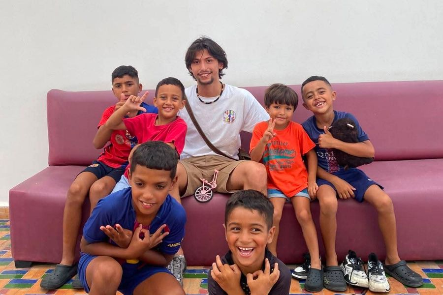 Un volontario con un gruppo di bambini sorridenti seduti su un divano